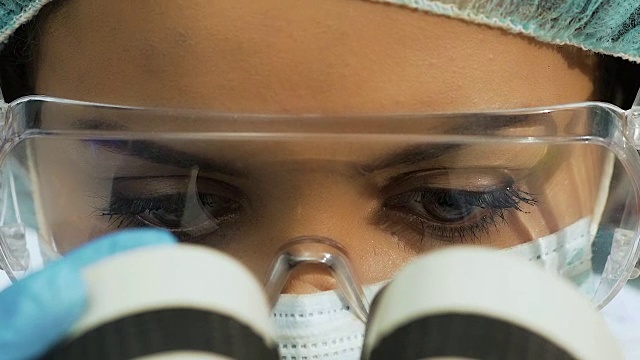 迷人的女科学家在显微镜下研究微生物，近距离视频素材