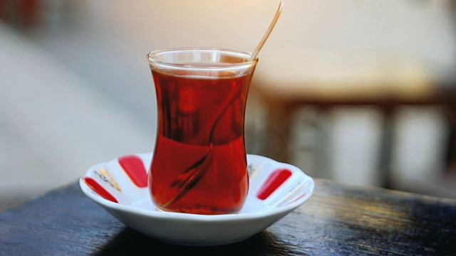 路边茶馆的桌子上放着一杯特制的土耳其茶，背景上是一些模糊的人视频素材