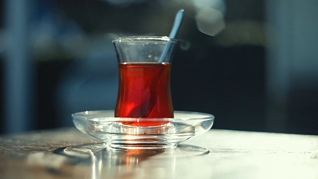 路边茶馆的桌子上放着一杯特制的土耳其茶，背景上是一些模糊的人视频素材