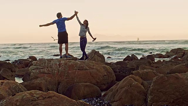 日落时分，情侣们在海滩上锻炼后击掌庆祝视频素材