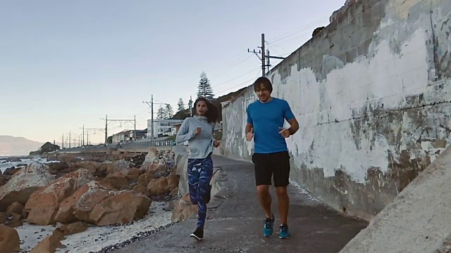 一对健康的夫妇在海滩边慢动作跑步锻炼视频素材