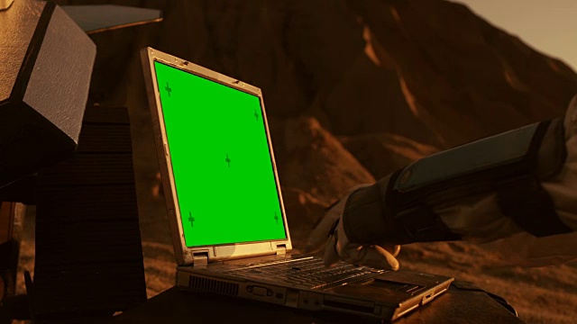 外星人红色星球/火星上的宇航员在一台绿屏笔记本电脑上工作。太空探索，寻找可居住的世界和殖民。视频下载