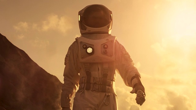中景宇航员穿着宇航服探索火星/红色星球。第一次载人火星任务，技术进步带来了太空探索和殖民。视频素材