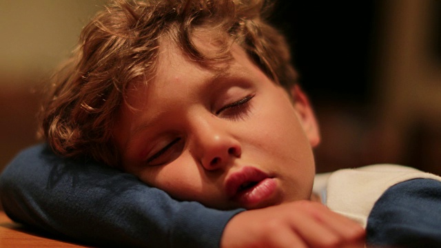 可爱的孩子沉睡在深度睡眠瘫痪状态。小男孩在漫长的一天的活动中疲惫不堪地做梦。孩子在桌子上休息和睡觉视频素材