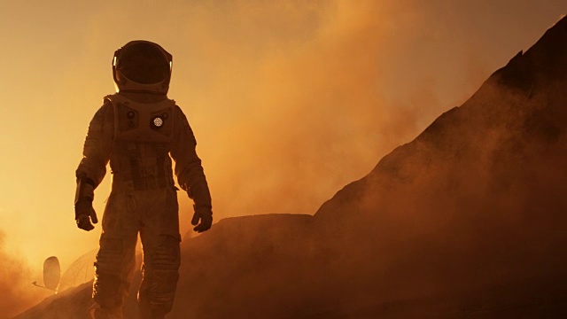 骄傲的宇航员自信地在火星表面行走。被气体和岩石覆盖的红色星球，克服困难，人类的重要时刻。视频下载