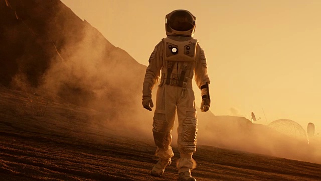 骄傲的宇航员自信地在火星表面行走。被气体和岩石覆盖的红色星球，克服困难，人类的重要时刻。视频素材