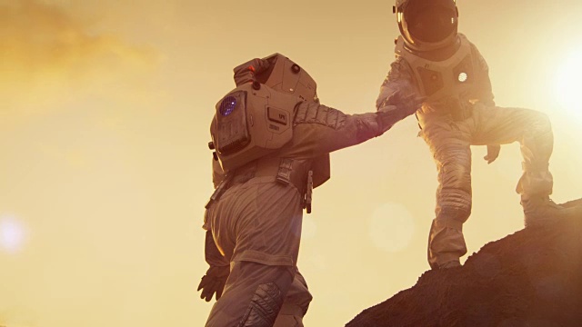 两名宇航员爬山互相帮助，到达顶峰。援助之手。克服困难，人类的重要时刻。视频素材