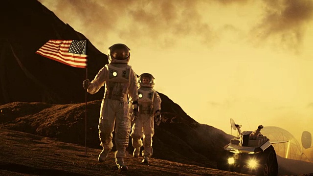 两名宇航员探索火星/红色星球。一个举着美国国旗。不久的将来和技术的进步带来了太空探索，旅行，殖民的概念。视频下载
