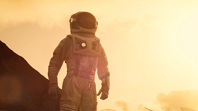 宇航员站在火星/红色星球上环顾四周，双手叉腰。背景:他的基地/研究站。太空探索，殖民主题。视频素材