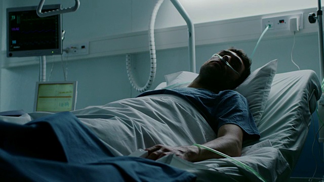 在医院里，一名绝症患者躺在床上忍受痛苦。年轻男子在姑息治疗病房。视频素材