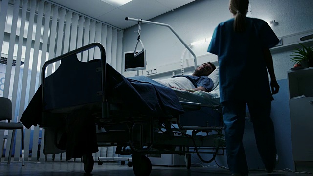低水平射击，重病人躺在床上，护士检查他的生命体征和跌落计数器。视频素材