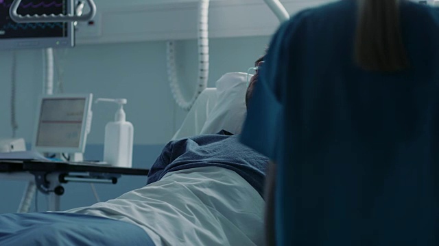 在医院生病的男性病人睡在床上，护士进入医疗病房检查他的生命体征和跌落计数器。悲伤和蓝色的场景。视频素材