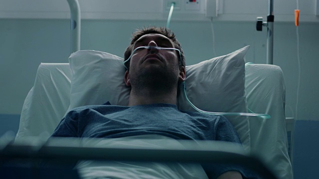 在医院生病的男性病人睡在床上，他戴着鼻导管帮助他呼吸。即将到来的绝症患者。悲伤和蓝色的场景。视频素材
