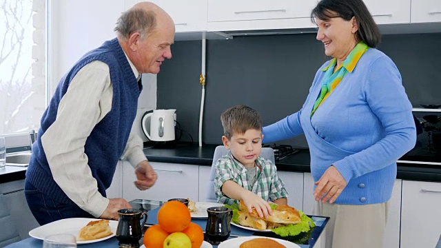 退休老人夫妇拥抱孩子在午餐时间在厨房旁边的桌子上美味的食物视频下载