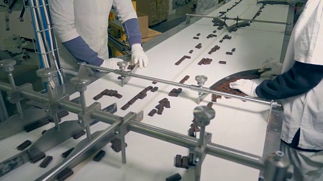 俯视图的巧克力糖果得到分拣工人和进一步沿着传送带移动视频下载