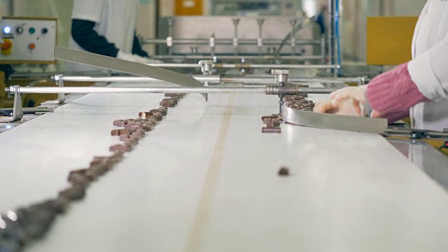 巧克力棒被工人们分拣后正在传送带上缓慢移动视频下载