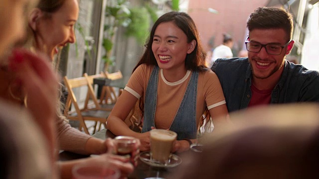 年轻的多民族潮夫妇有乐趣与朋友在咖啡馆视频素材