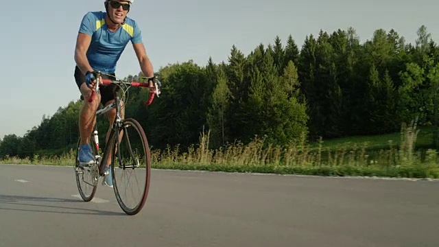 低角度:在大自然中训练的男性公路自行车手追上并超过了相机。视频素材