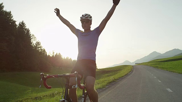 太阳耀斑:公路比赛的获胜者高兴地挥舞着他的手臂，不用手骑自行车。视频素材