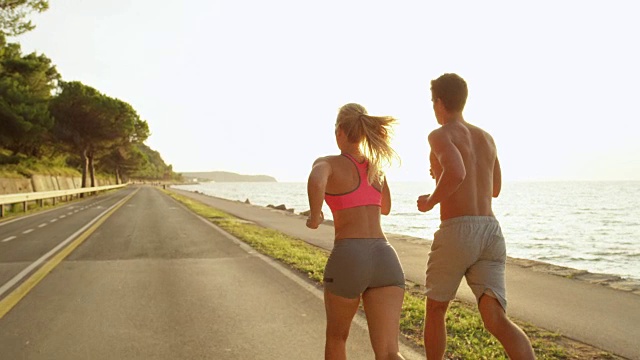 太阳耀斑:一对不认识的活跃夫妇在美丽的阳光灿烂的海洋大道上奔跑。视频素材