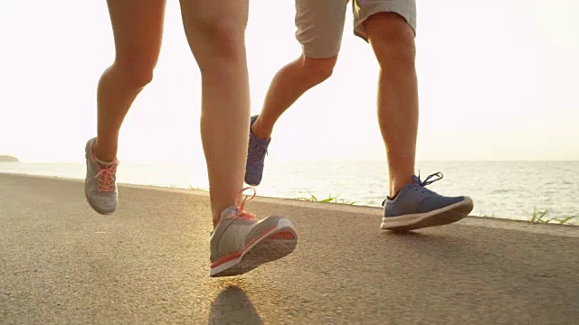慢镜头:穿着运动运动鞋的慢跑者在海滩附近奔跑。视频素材