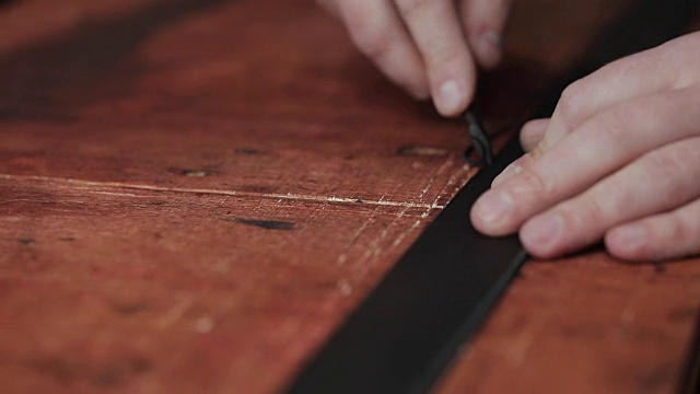 皮带在皮革车间的工作过程。手持制作工具的人正在工作。旧制革厂的皮匠。木桌上的背景。视频下载