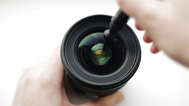 新手摄影师或视频摄影师正在用专业的光学清洁笔仔细清洁镜头前的玻璃视频下载