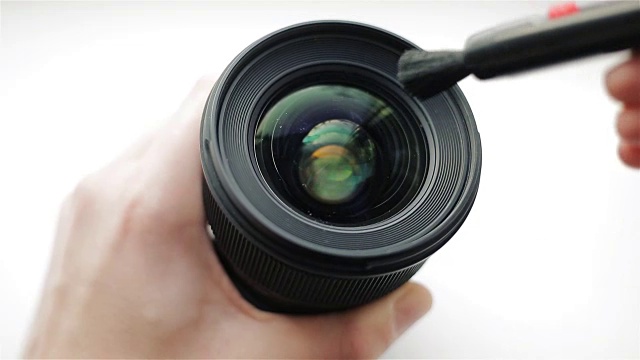 摄影师或摄像师用专业的清洁笔清洁镜头前的灰尘和污垢。用刷子清洁现代相机镜头视频素材