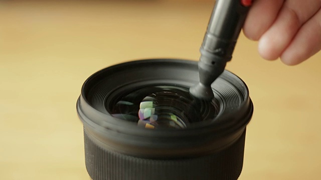 新手摄影师或视频摄影师正在用专业的光学清洁笔仔细清洁镜头前的玻璃视频素材