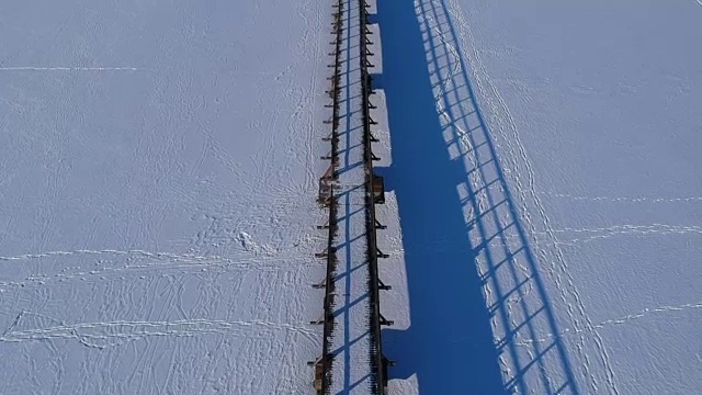 无人机飞越雪湖木桥视频素材