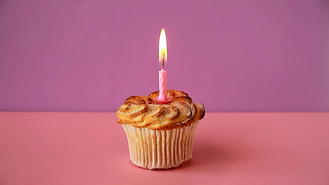 生日的纸杯蛋糕和一支点燃的蜡烛。时间流逝的视频视频素材