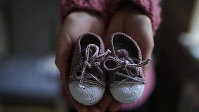 女性的手展示婴儿的靴子。儿童针织鞋视频下载