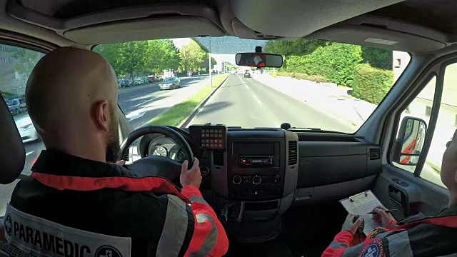 一名男性护理人员驾驶着救护车，而他的队员在写字板上写字视频下载