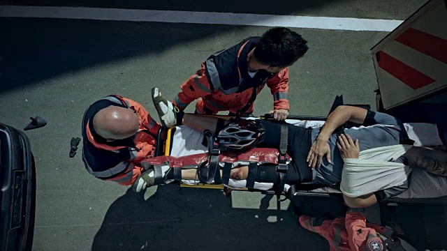CS医护人员将一名受伤的摩托车手抬到救护车上视频素材
