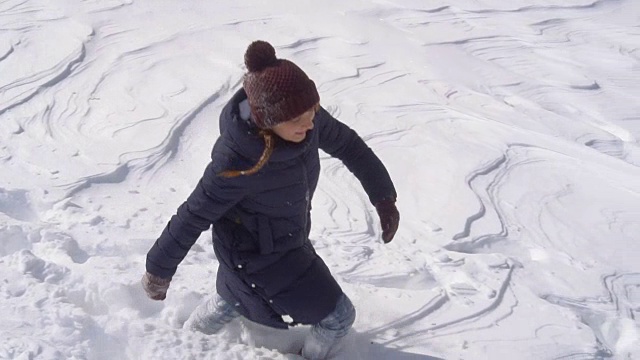 美丽的年轻女子走在深深的雪地里视频素材