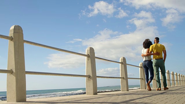 一对情侣在一个晴朗的日子里一起在沙滩上散步视频素材