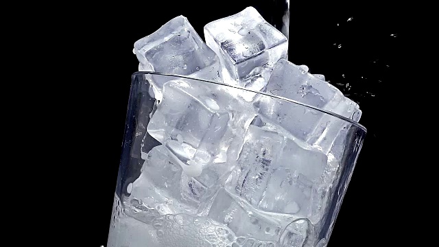 以慢动作将水倒入装有冰块的玻璃杯中视频素材