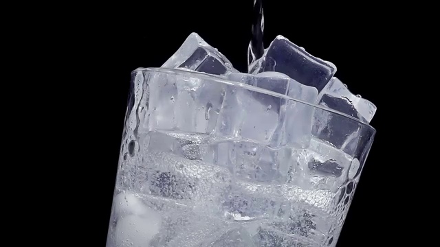 以慢动作将水倒入装有冰块的玻璃杯中视频素材