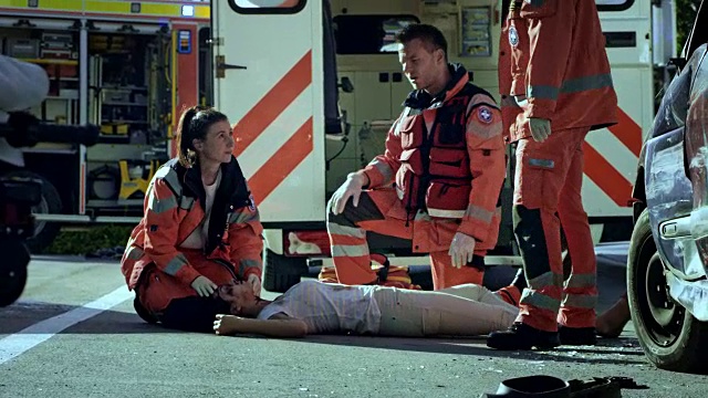 在车祸现场，紧急医疗服务小组正在检查一名躺在地上的年轻女子的生命体征视频下载