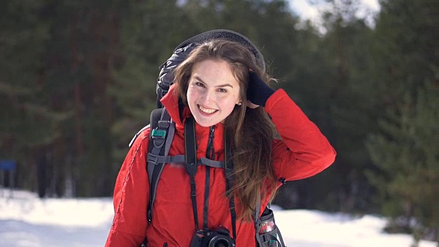 一个快乐的游客在阳光明媚的冬季森林的肖像。视频下载