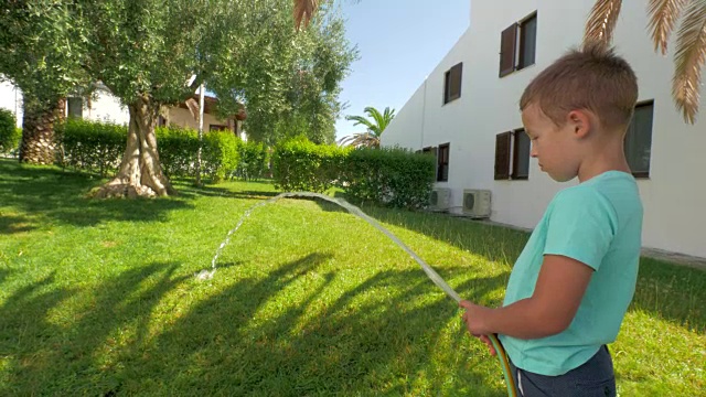 孩子参与家务劳动，浇灌房子旁边的绿色草坪视频素材