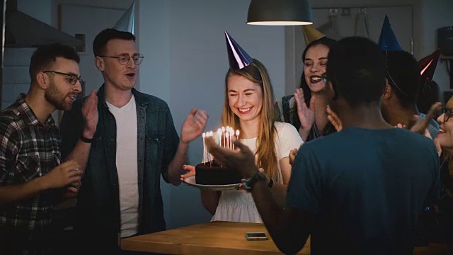 快乐的白人女孩许了一个生日蛋糕愿望。不同的团体一起庆祝朋友的节日。神奇的时刻。4 k视频素材
