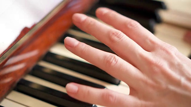 女性手指在复古钢琴键盘上弹奏琴键。景深浅。专注于手视频素材