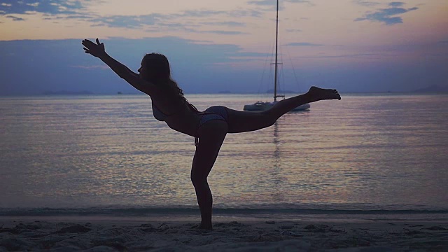 年轻女子练习瑜伽，在美丽的日落海滩上做姿势。缓慢的运动。1920 x1080视频素材