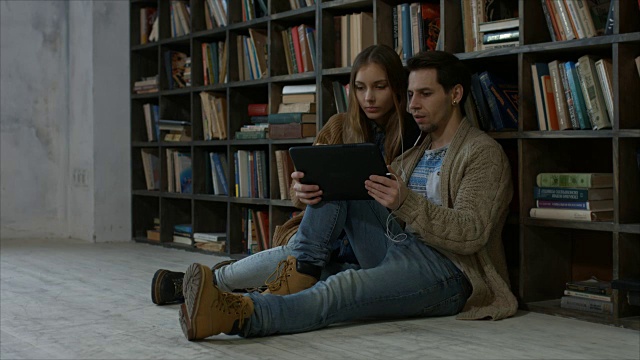 微笑的学生夫妇在图书馆使用平板电脑视频素材
