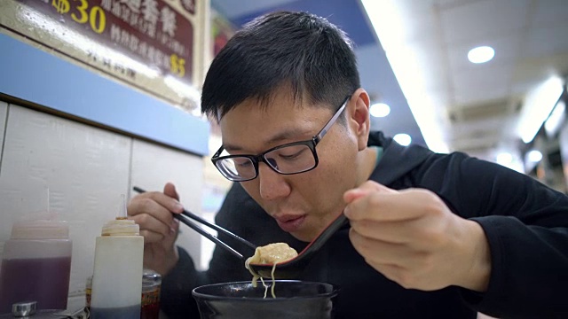 一名亚洲男子在餐厅吃香港汤面视频素材