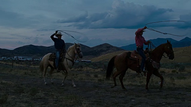 两个年轻人练习套索骑马在晚上在犹他州，美国的实时视频视频素材