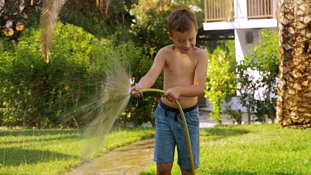 孩子用软管浇草坪视频素材