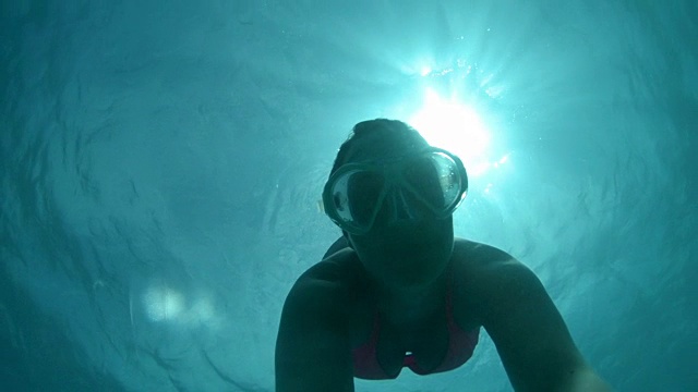 水下自拍:年轻女子在翠绿的海洋中潜水时调节压力视频素材