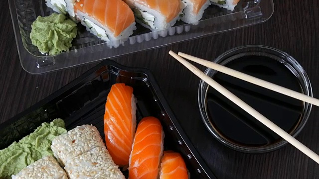 在时尚的黑色背景上，配有各种寿司卷以及寿司卷、手握寿司、粗看。靠近酱油和竹竿。俯视图视频下载